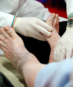 Photo: A podiatrist examining the injured feet of an elderly person