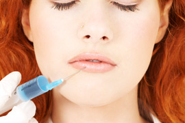 A woman getting a filler injection in her lower lip