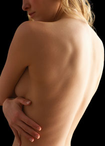 Side profile of a bare woman's upper body with her arms across her breasts